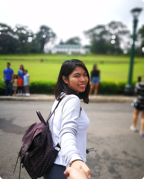 A college student smiling outdoors, starting their program journey.